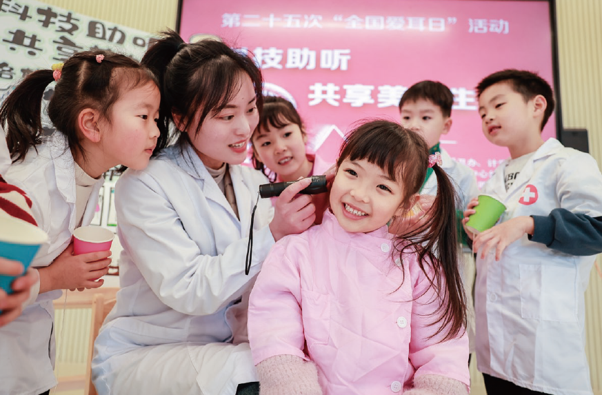2024年3月1日，浙江省湖州市長興縣龍山街道中心幼兒園內(nèi)，保健醫(yī)生正在 為孩子們開展耳朵健康檢查。