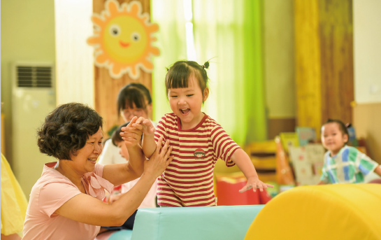 近年來，各地著力解決3歲以下嬰幼兒家庭入托難、入托貴等 問題，大力發(fā)展完善普惠托育服務(wù)體系，不斷增強(qiáng)人民群眾對(duì)普惠 托育服務(wù)的獲得感和滿意度，促進(jìn)嬰幼兒健康成長(zhǎng)。圖為2024年 9月4日，江西省奉新縣示范幼兒園托育班的老師和孩子們?cè)诳鞓?地玩耍。