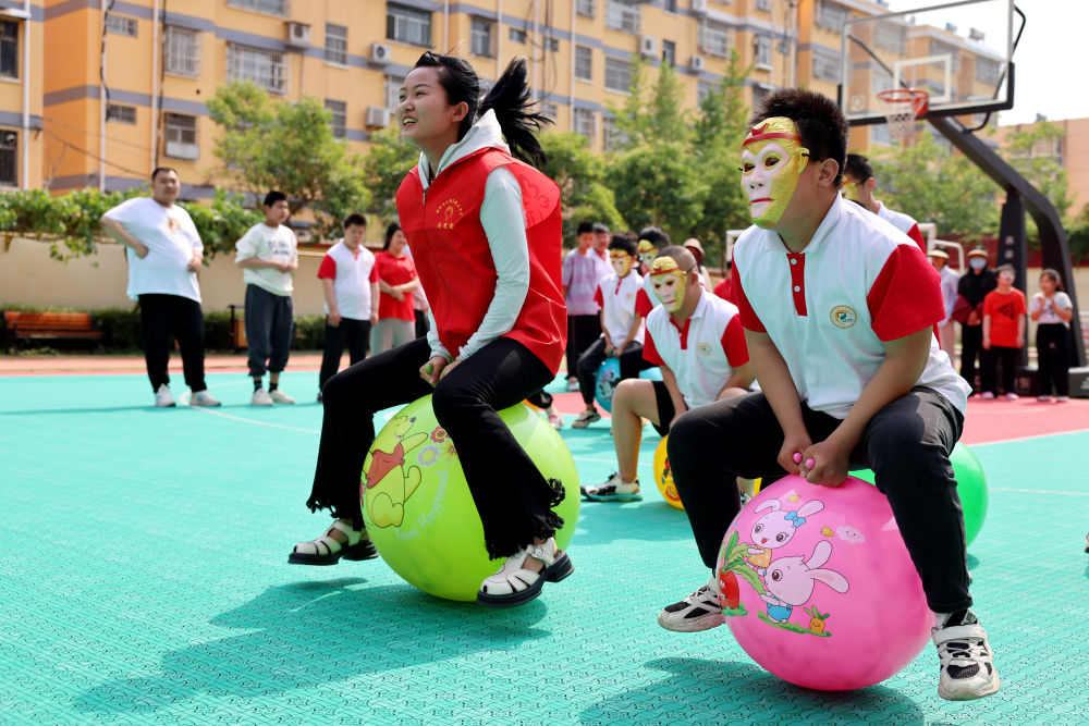 2024年5月17日，在山東省棗莊市市中區(qū)特殊教育中心，青年志愿者與智力障礙學生一起做游戲。新華社發(fā)（孫中喆攝）